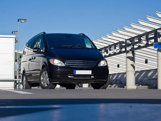 Van Mercedes nero parcheggiato su una superficie asfaltata sotto una struttura moderna
