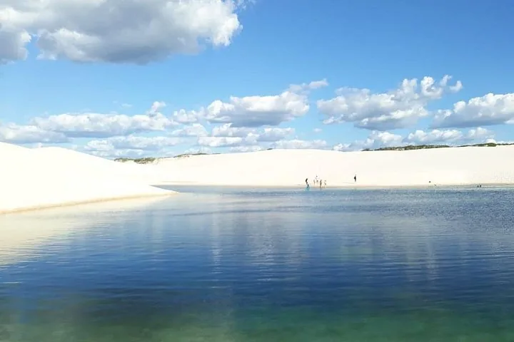 Klare blaue Lagune, die den Himmel spiegelt, umgeben von weißen Sanddünen.
