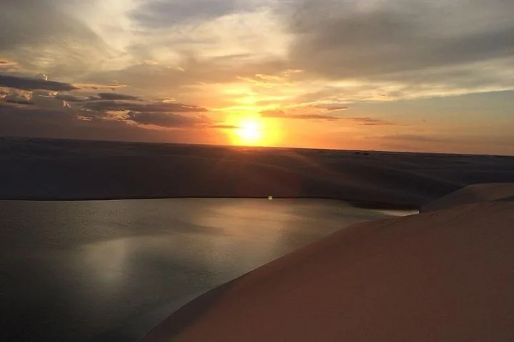 Atardecer sobre dunas de arena blanca y una laguna oscura