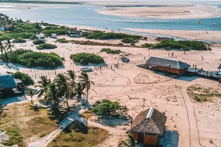 Luftaufnahme eines Küstendorfs mit Sandwegen und strohgedeckten Gebäuden