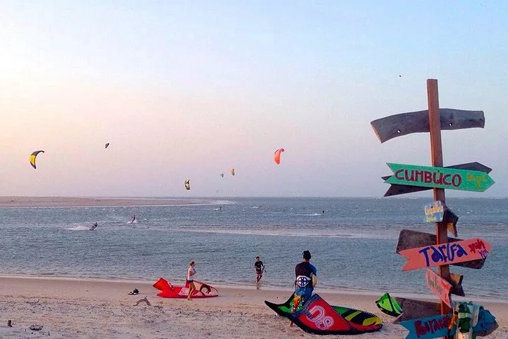 Kitesurfer an einem Strand mit einem bunten hölzernen Wegweiser